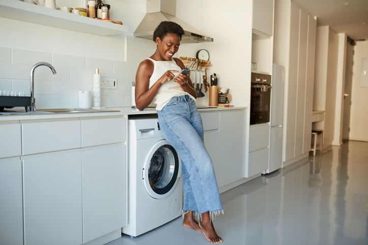 Shot of a young woman using a smartphone in the kitchen at home