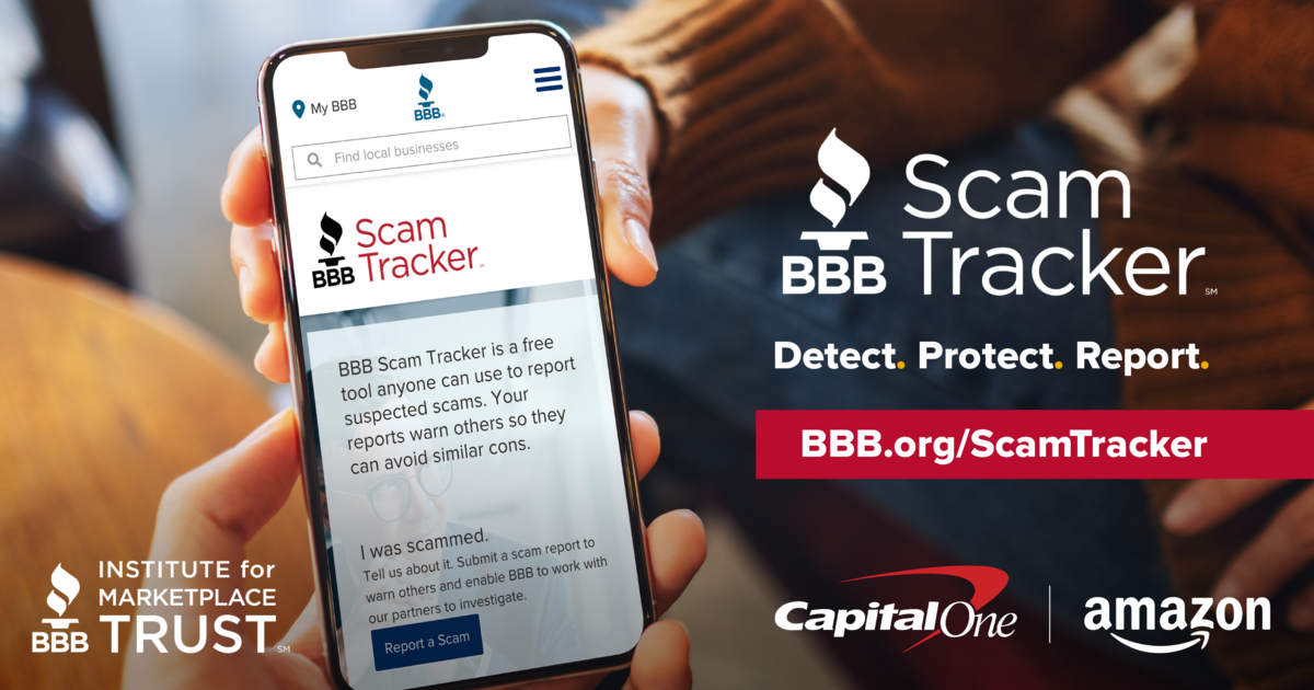 Hand holding a phone showing the Scam Tracker website