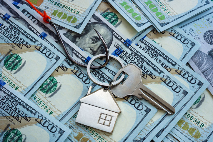 Real estate fraud concept. The hook and the key to house lie on the money.