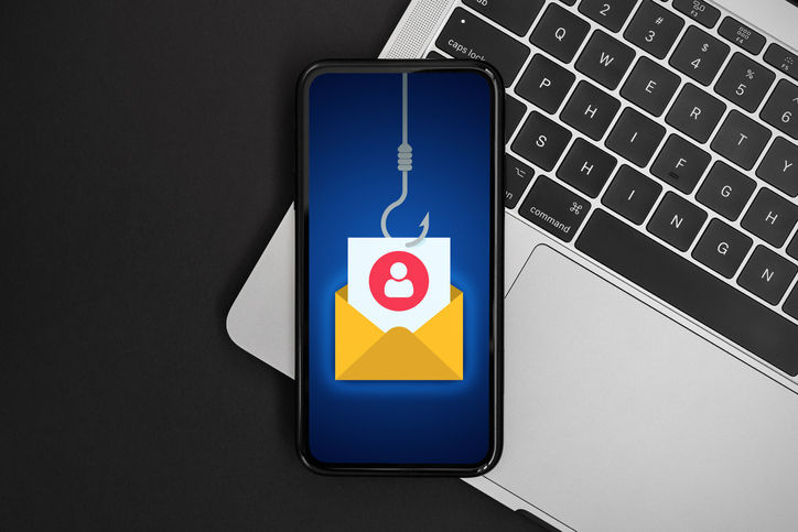 Phishing bait alert concept on a mobile phone screen over a laptop