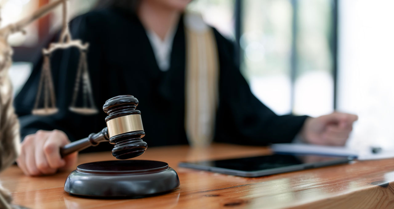 Woman judge hand holding gavel to bang on sounding block in the court room.