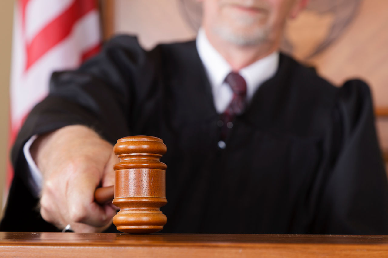 A close-up of a judge's gavel in his hand in the courtroom.