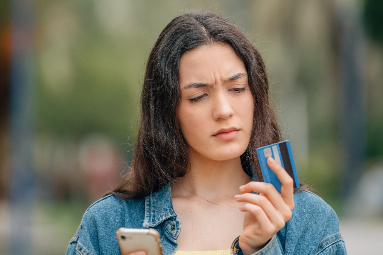 girl with mobile phone and credit card with expression of doubt or mistrust