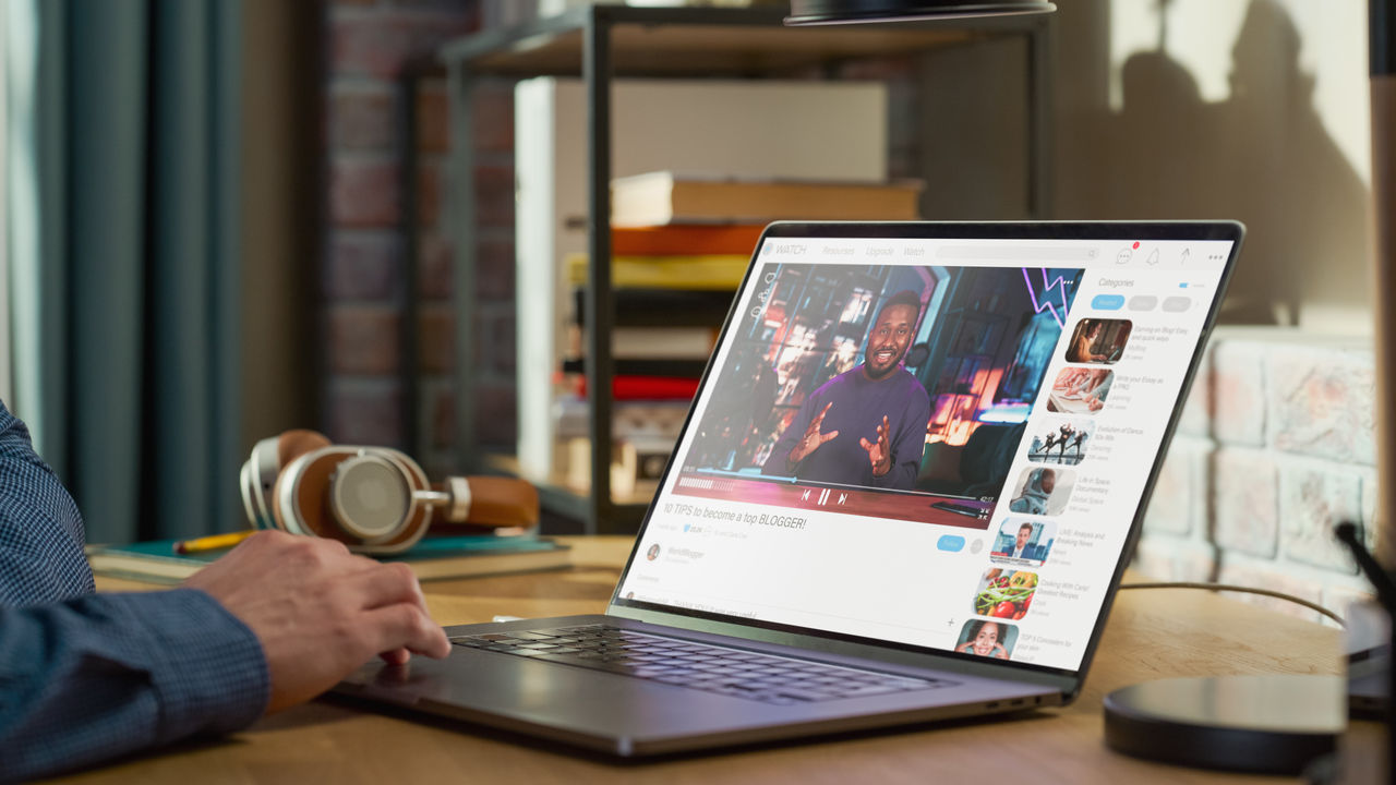 Close Up on Male Hands Using Laptop to Watch Video Sharing Service Mock-up Where African American Influencer Talks About Lifestyle. Interface with Related Streams, Likes, Comments.