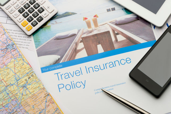 Travel insurance policy document with paperwork and technology. There is an image of a tourist resort with cocktails and a swimming pool which adds to the peace of mind concept. There is also a mobile phone, map, digital tablet and calculator. Image featured on the brochure can be found in my portfolio 20943516