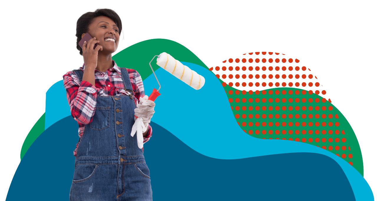 african american woman holding smart phone and paint roller
