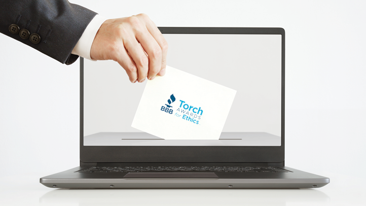 Man putting a ballot with BBB Torch Awards logo into a laptop