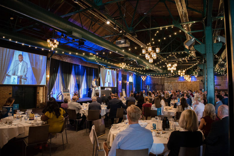 An audience sits and watches keynote speaker Tony Sanneh on stage at the 2023 BBB Torch Awards for Ethics celebration