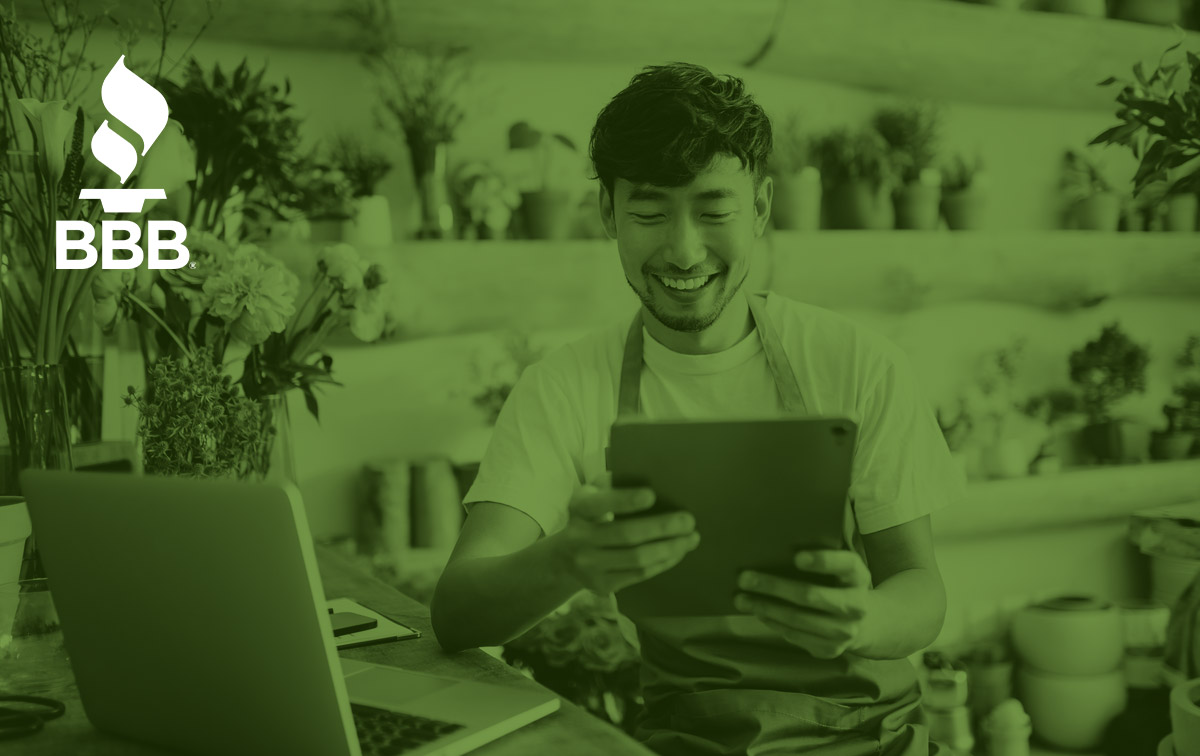 Male florist looking at tablet and smiling.