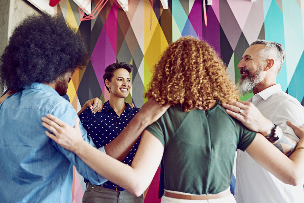 Shot of a group of designers standing in a huddle in an office