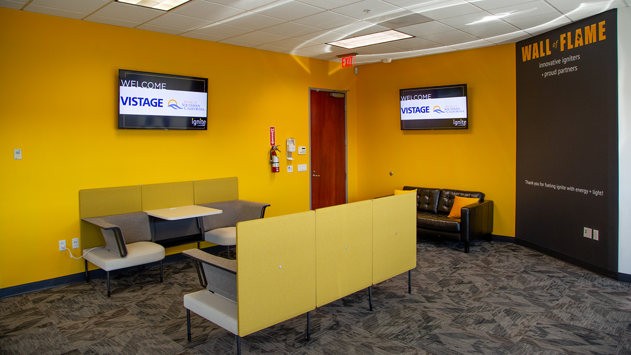 booth style seating options with yellow and dark gray walls and tv screen in the background