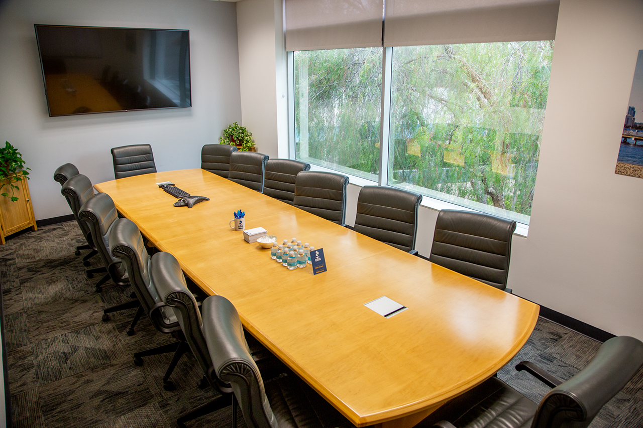 long conference table with windows looking out on the street and large tv on the wall