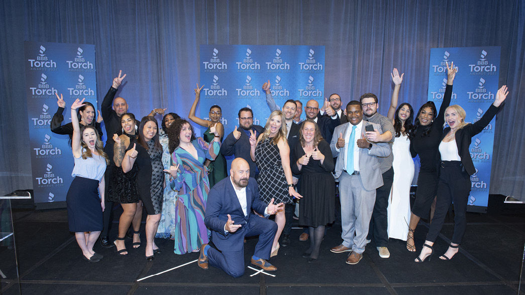 Diverse group of BBB employees taking a fun photo on stage at out annual Torch Awards for Ethics in Phoenix, Arizona